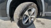 Close-up of a tire and alloy wheel mounted on a vehicle, showing tread and dirt on the tire and wheel well ripples nearby.