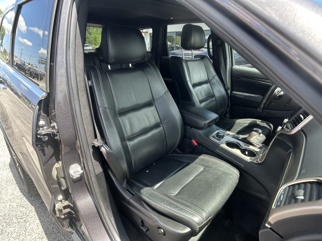 Interior of a black leather SUV with front seats, center console, and steering wheel visible from the open driver's side door