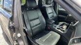 Interior of a black leather SUV with front seats, center console, and steering wheel visible from the open driver's side door