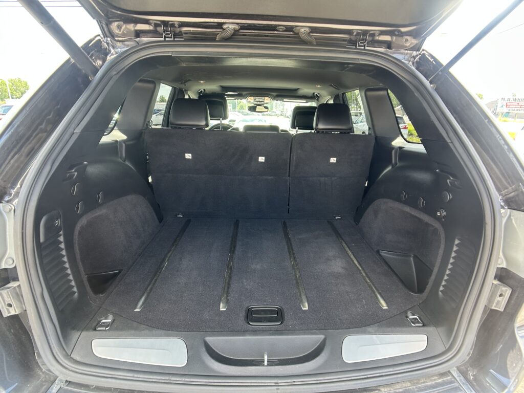 SUV cargo area with third-row seats upright, view from rear hatch, showing black upholstery and L-track rails in the floor