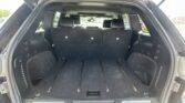 SUV cargo area with third-row seats upright, view from rear hatch, showing black upholstery and L-track rails in the floor