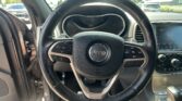 Close-up of a Jeep steering wheel with the instrument cluster and center console visible, parked in a lot outside the car.