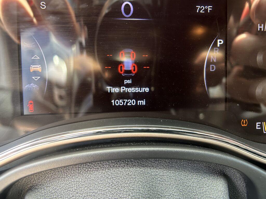 Vehicle dashboard: tire pressure warning with red '0' readings around car icon, speed 0, odometer 105,720 miles, gear in Park, 72°F.