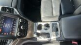 Center console of a car interior with a touchscreen, climate controls, cup holders, and leather seating