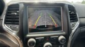 Car dashboard screen showing rearview camera with colored guidance lines for parking.