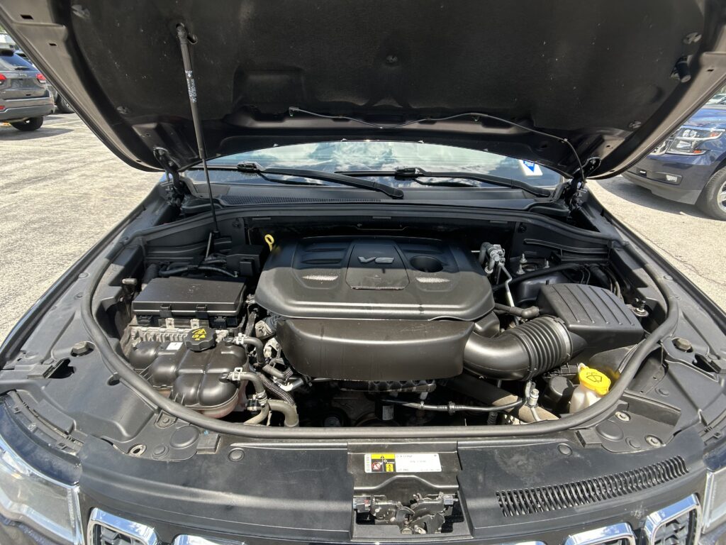Open hood of a vehicle showing the engine bay with components and wiring visible under bright daylight