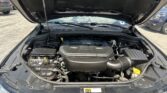 Open hood of a vehicle showing the engine bay with components and wiring visible under bright daylight