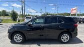 Black Chevrolet Equinox SUV parked in a dealership lot with power lines, blue sky, and an EZ Loan Auto Sales sign in the background.