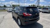 Black Chevrolet Equinox in the foreground of a busy parking lot on a sunny day, with white cars and power lines overhead.