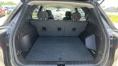 Open SUV cargo area with third-row seats upright and wide, empty trunk space visible from rear hatch