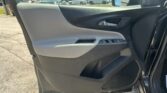 Interior of a car door panel with power window/lock controls, looking out at a busy parking lot with many vehicles.