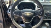 Driver’s perspective of a Chevrolet steering wheel and instrument cluster, with a parking lot visible through the windshield