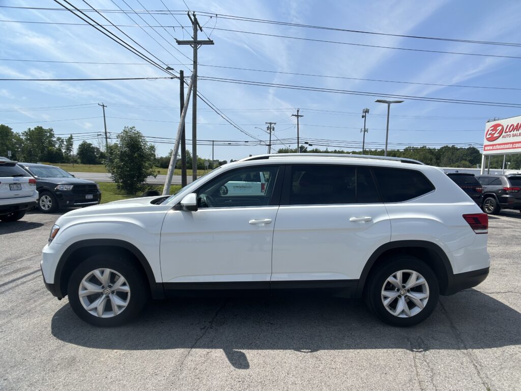 White SUV in a parking lot with utility poles and multiple power lines overhead on a sunny day.