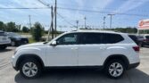 White SUV in a parking lot with utility poles and multiple power lines overhead on a sunny day.