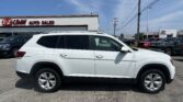 White SUV in a dealership lot in front of a white building with an EZ Loan Auto Sales sign; a Toyota showroom is visible in the distance, blue sky above. strategic