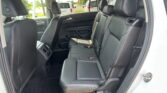Rear passenger area of a modern SUV with black leather seats and visible seat belts, viewed from the open rear door edge.