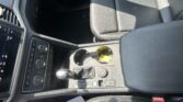Center console area of a car showing the gear shifter, climate controls, and cup holders with a yellow tag inside the cup holder.