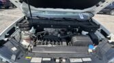 Front of a car with the hood up, exposing the engine bay and VW emblem at the grille.