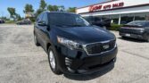 Black Kia SUV in the foreground at a sunny used-car lot, EZ Loan Auto Sales sign visible on the building in the background.