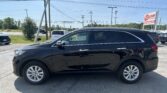 Black Kia SUV in a car dealership lot with power lines and an EZ Loan Auto Sales sign in the background, sunny day