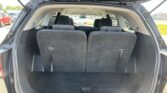 SUV rear hatch open; third-row seats upright, exposing the cargo area with dark gray carpeting and black upholstery.