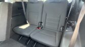Backseat of a car showing two gray patterned captain chairs with seat belts and a cup holder on the right side.