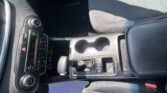Interior of a car front cabin showing the center console with gear shifter, cup holders, and climate controls on the left-side dashboard edge.