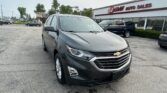Gray Chevrolet SUV in the foreground at a car dealership lot, EZ Loan Auto Sales in the background.