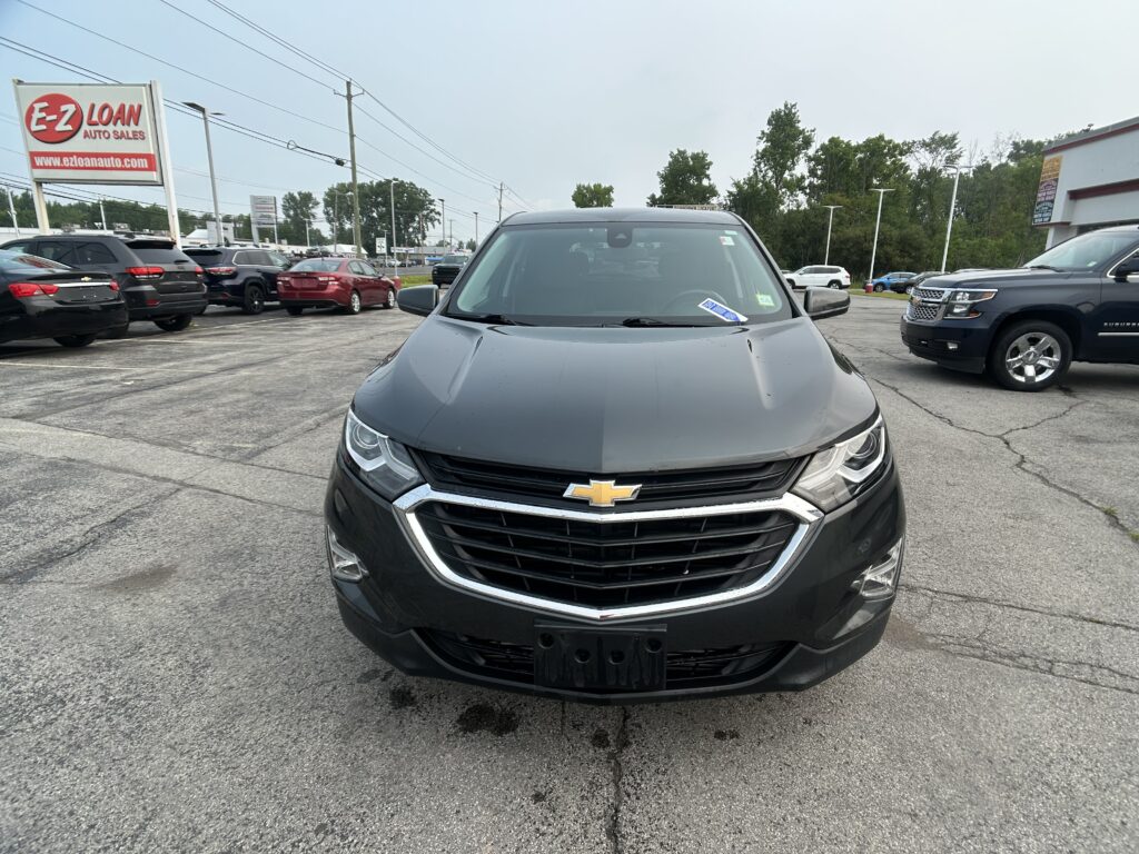 Front view of a dark gray Chevrolet SUV parked in a dealership lot with an E-Z LOAN Auto Sales sign visible in the background.