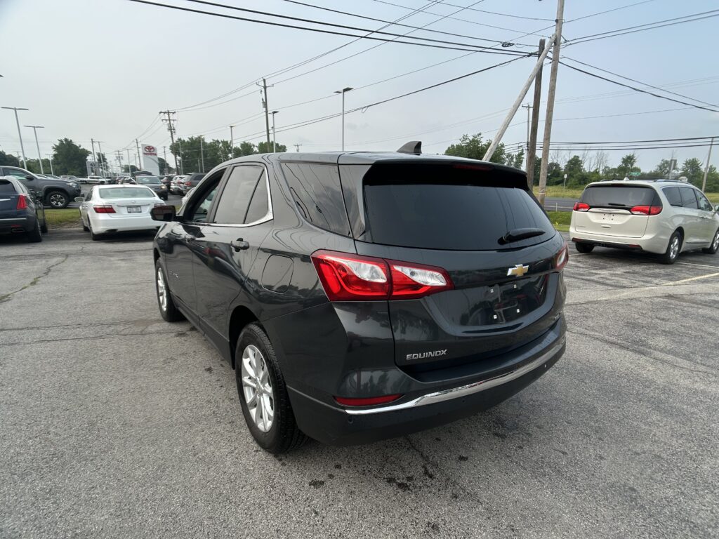 Rear view of a black Chevrolet Equinox in a crowded parking lot with power lines overhead.