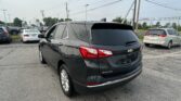 Rear view of a black Chevrolet Equinox in a crowded parking lot with power lines overhead.