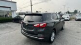 Rear three-quarter view of a dark-gray Chevrolet SUV in a car dealership lot with rows of cars and a Toyota dealership building in the background.