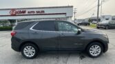 Dark gray Chevrolet Equinox parked in a car dealership lot in front of an E-Z Loan Auto Sales storefront.