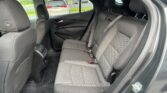 Rear passenger area of a car with black fabric seats, visible three-point seat belts, and headrests