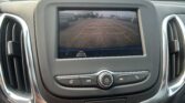 Car backup camera view: parking lot with yellow guide lines on screen, showing surrounding vehicles behind the car