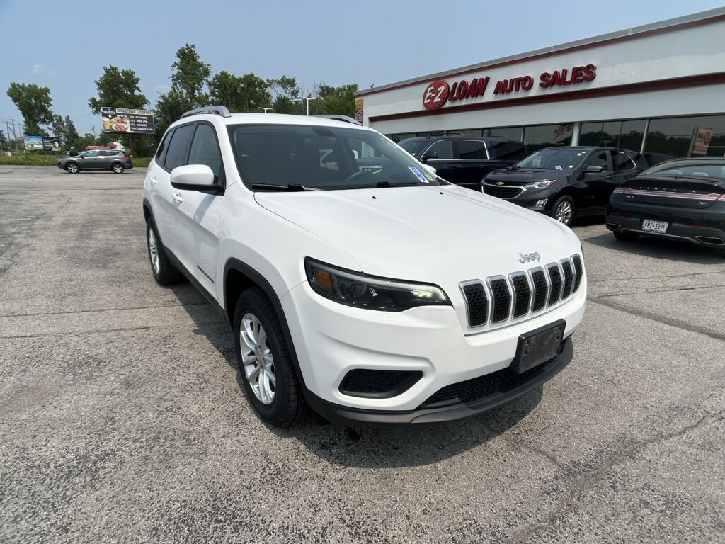 White Jeep SUV in the dealership lot with E-Z Loan Auto Sales building in the background.