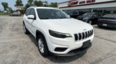 White Jeep SUV in the dealership lot with E-Z Loan Auto Sales building in the background.