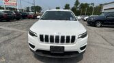 Front view of a white Jeep SUV in a car dealership lot with a tall E-Z LOAN Auto Sales sign in the background on the left.