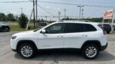 White SUV (Chrysler Cherokee) parked in a car lot with power lines overhead and an EZ Loan Auto Sales sign in the background.