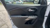 Interior of a car door panel with window controls; the parking lot is visible through the open window and reflected in the side mirror.