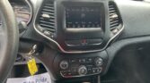Interior of a car dashboard showing a touchscreen infotainment system, central controls, and steering wheel on the left side, with papers on the floor reading 'We Take Pride In Your Vehicle'.