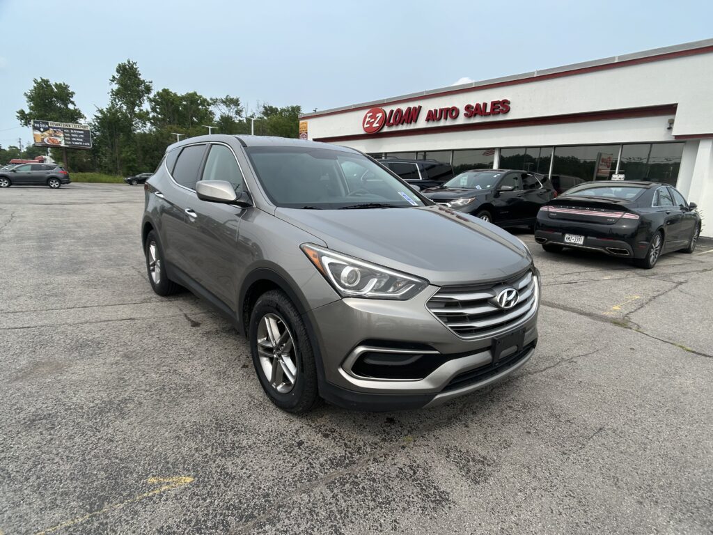 Grey Hyundai SUV in foreground at a car dealership lot with EZ Loan Auto Sales storefront in the background.