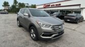 Grey Hyundai SUV in foreground at a car dealership lot with EZ Loan Auto Sales storefront in the background.