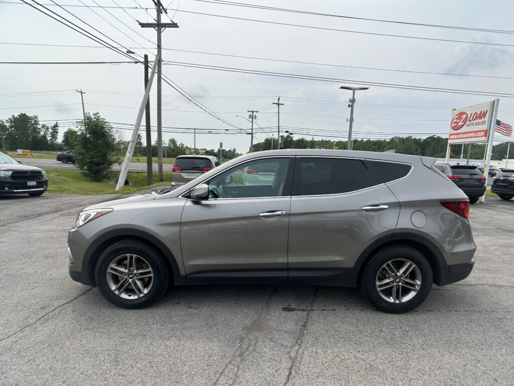Silver SUV parked in a dealership lot, with an EZ Loan Auto Sales sign visible in the background and overhead power lines.