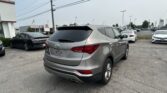 Silver Hyundai SUV in foreground at a car dealership lot with many vehicles and a Toyota showroom in the background