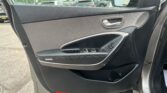 Interior of a car's front left door: gray panel, chrome door handle, window controls, and side mirror visible through the windowening scene