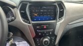 Car interior dashboard with a touchscreen stereo on FM 98.50, flanked by air vents and center controls.