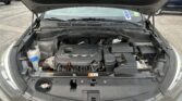 Front view of an car with its hood open, exposing the engine bay and components under the hood in a parking lot