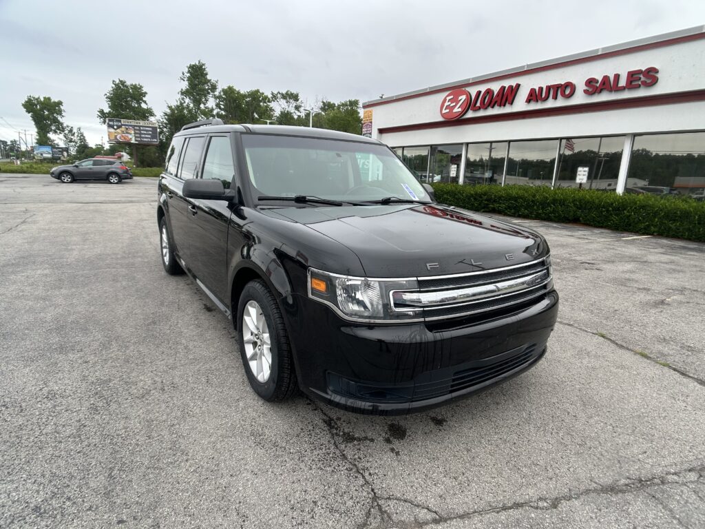 Black Ford SUV in a dealership lot with EZ LOAN AUTO SALES building in the background and a gray car parked nearby.
