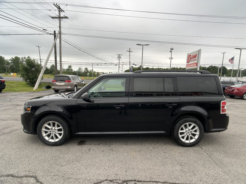 Black SUV parked in a dealership lot with power lines and a Lion Auto Sales sign in the background.